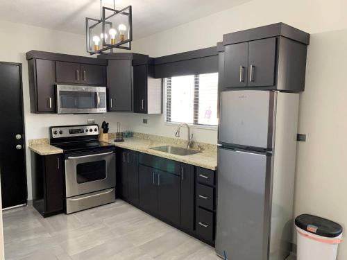 a kitchen with black cabinets and a stainless steel refrigerator at Casita de Moana in Puerto Peñasco