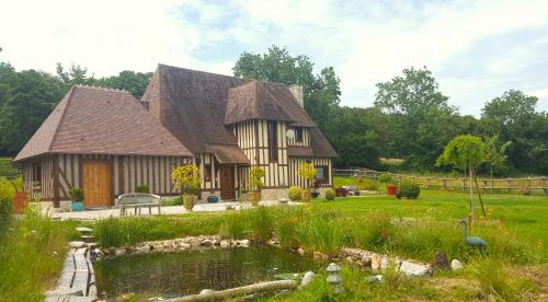 a house with a pond in front of it at L'Herbe aux Vaches in Saint-Pierre-Azif