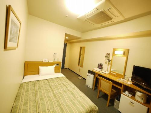 a room with a bed and a desk and a television at Hotel Route-Inn Osaka Honmachi in Osaka