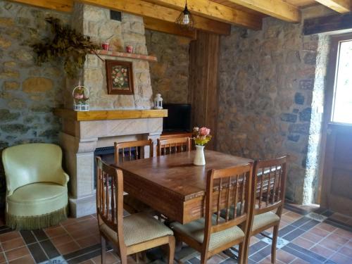a dining room with a table and chairs and a fireplace at Casa de Aldea La Xunta in Cangas de Onís