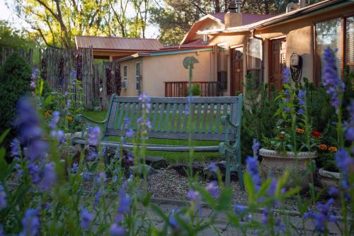 a green bench in a garden with purple flowers at Dreamcatcher B&B in Taos