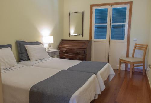 una camera con due letti, una sedia e uno specchio di Apartments Madeira Santa Maria a Funchal