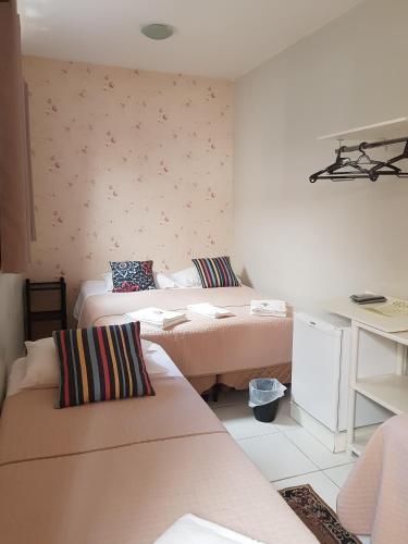 a small room with two beds and a desk at Pousada Cantinho DelMar in Olímpia