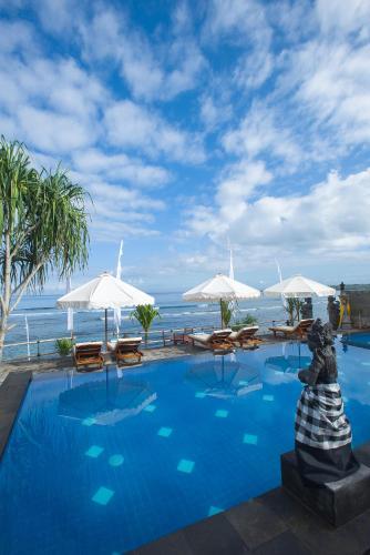 a swimming pool with chairs and umbrellas next to the ocean at Twilight Ceningan in Nusa Lembongan