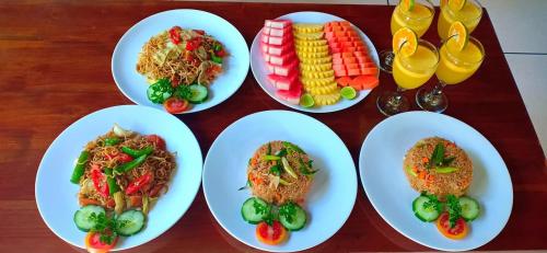 four white plates of food on a wooden table at Bali Harmony Villa in Ubud