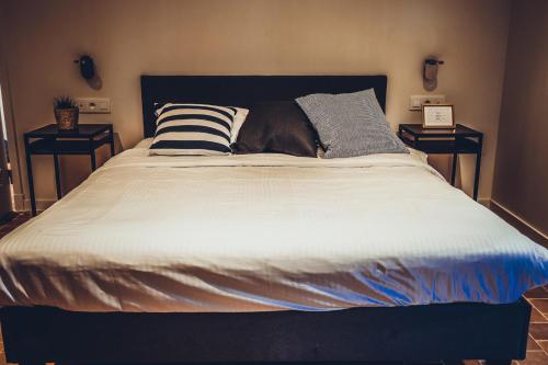 a large bed in a bedroom with two end tables at Colonie 7 - Gastenkamers in Merksplas