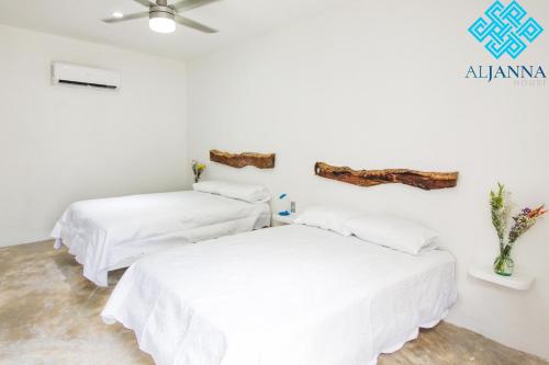 two beds in a room with white sheets at Aljanna House in Bacalar