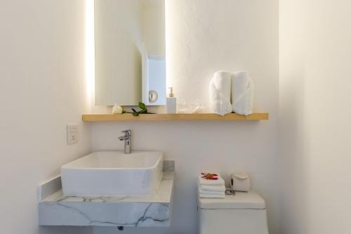 a white bathroom with a sink and a toilet at Studios Downtown Cancun in Cancún