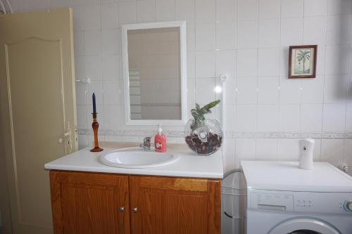een badkamer met een wastafel en een wasmachine bij Lemos family beach house in Nazaré