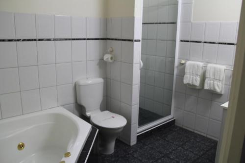 a bathroom with a tub and a toilet and a shower at Bright Avenue Motor Inn in Bright