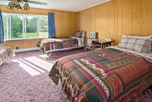 a bedroom with two beds and a desk and a window at Talkeetna Inn in Talkeetna