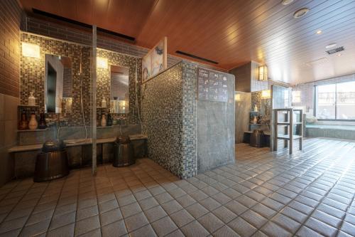 a bathroom with a shower and a tiled wall at Dormy Inn Morioka in Morioka