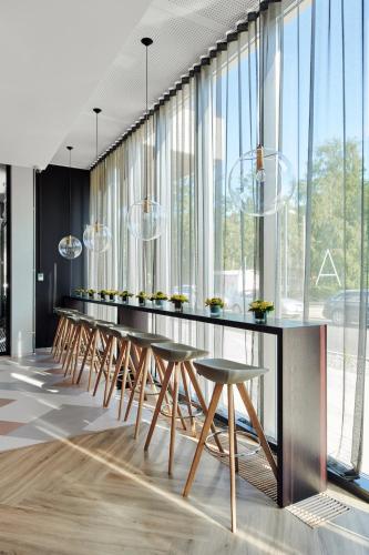 Una larga fila de mesas y sillas en una habitación con ventanas. en Wasa Resort Hotel, Apartments & SPA, en Pärnu