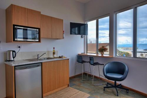 a kitchen with a sink and two chairs and windows at Cloudscape Apartment No 2 in Kingscote