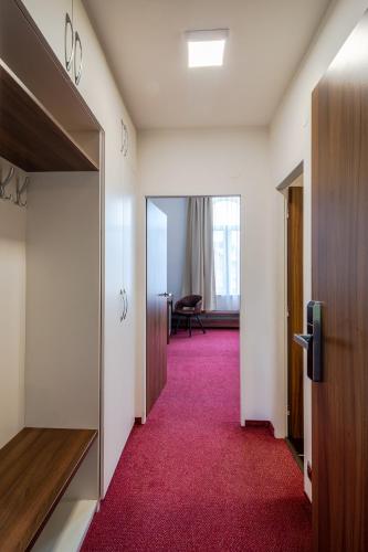 a hallway with a red carpet and a room with a door at Bohemia Inn Hotel in Turnov