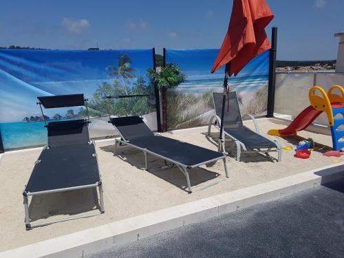 a beach with two chairs and an umbrella and a playground at O Paraíso no Terraço in Foz do Arelho