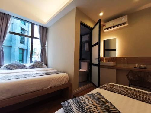 a room with two beds and a bathroom with a sink at Oikos Poshtel in Kota Kinabalu