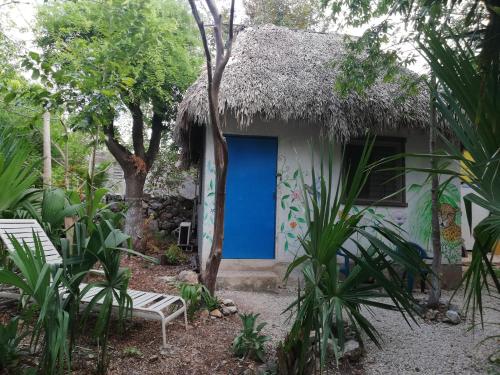 a small house with a blue door in a garden at Mayan Bungalow Near Chichén in Chichén-Itzá