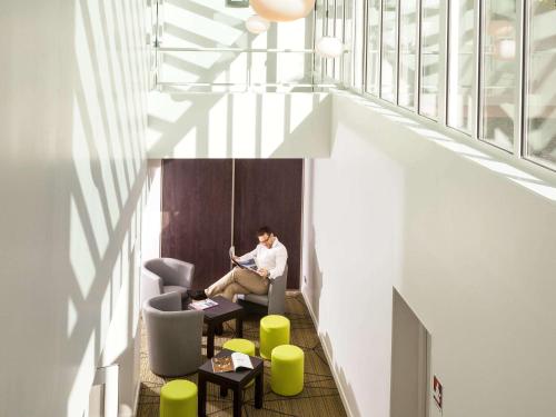 a man sitting in a chair in an office with a laptop at ibis Styles Saumur Gare Centre in Saumur