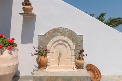 a white building with a statue and potted plants at Villa Aiolos in Palekastron