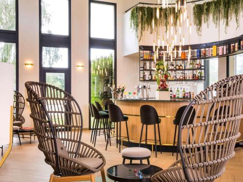 a restaurant with a bar with chairs and a chandelier at Mercure Orléans Portes de Sologne in Ardon