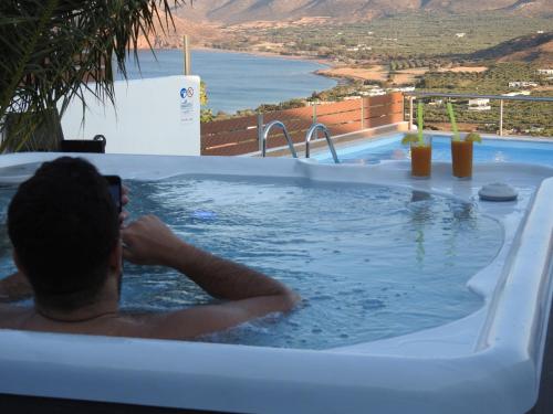 a man in a jacuzzi tub taking a picture of the ocean at Villa Aiolos in Palekastron