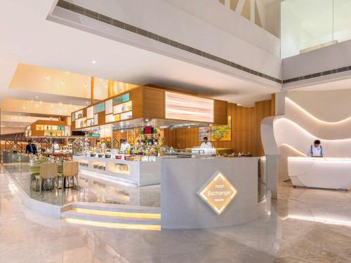 a restaurant with a bar with two people in it at Novotel Vijayawada Varun in Vijayawāda
