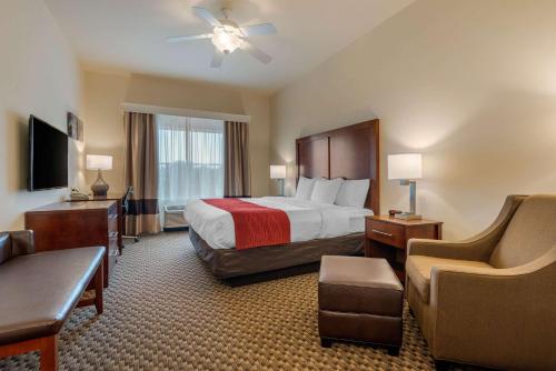 a large hotel room with a bed and a chair at Comfort Inn & Suites Fort Myers Airport in Fort Myers