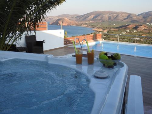 a pool with a table with drinks and fruit on it at Villa Aiolos in Palekastron