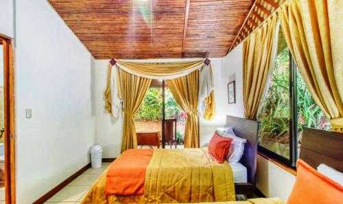 a bedroom with a bed and a large window at Hotel San Rafael Ecolodge in San Gerardo