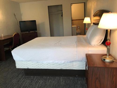 a hotel room with a bed and a desk and a television at Portland Super Value Inn in Portland