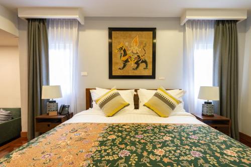 a bedroom with a large bed and two windows at Maneeya Park Residence in Bangkok