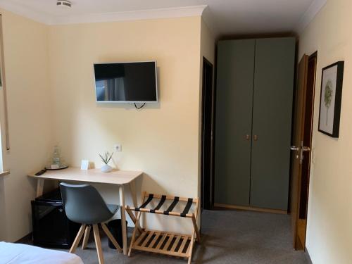 a room with a desk and a table and a tv at Hotel Augsburg Langemarck in Augsburg