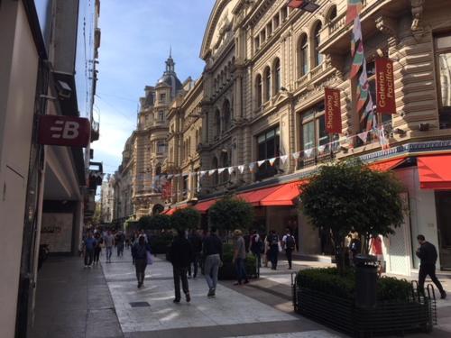 a group of people walking down a street with buildings at ApartFlorida3 in Buenos Aires