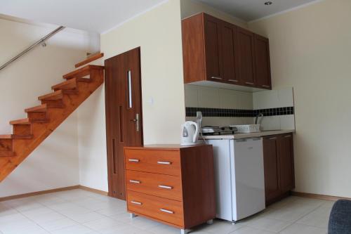 a kitchen with wooden cabinets and a staircase at Agroturystyka Rewita in Darłowo