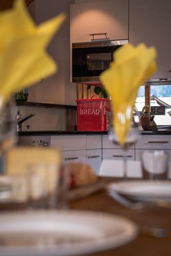 a kitchen with a table with yellow flowers in the foreground at Chalet Bella Vista 4 in Wengen