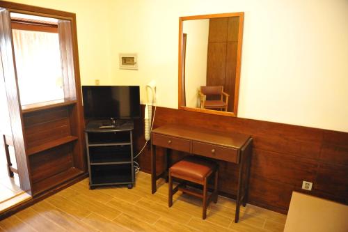 a room with a desk with a mirror and a television at Niki Hotel Apartments in Ialyssos