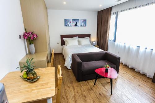a room with a bed and a couch and a table at Ficus Suites in Hanoi