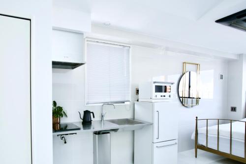 a white kitchen with a sink and a refrigerator at THE ROOT2 HOTEL in Kyoto