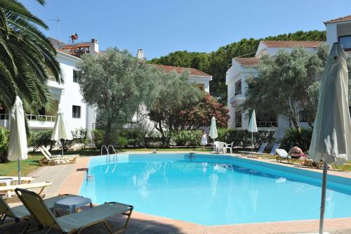 una grande piscina blu con sedie e ombrelloni di Niki Hotel Apartments a Ialyssos