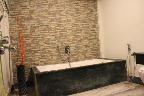 a bath tub in a bathroom with a brick wall at Tango Beach Resort in Neil Island