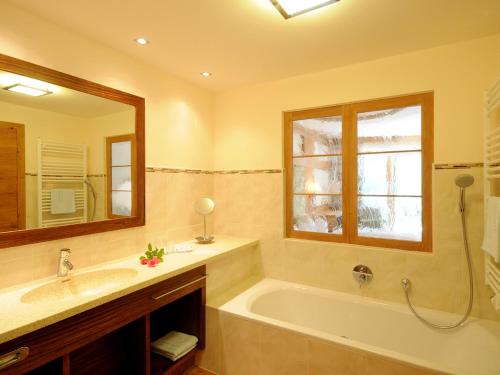 a bathroom with a tub and a sink and a mirror at Hotel Pramstraller in Mayrhofen