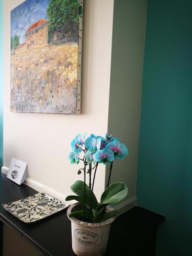 a potted plant sitting on a desk with a painting at En Suite in The Hague