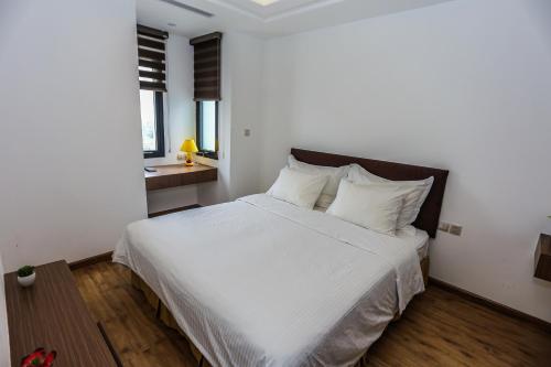 a bedroom with a large bed with white sheets and pillows at Ficus Suites in Hanoi