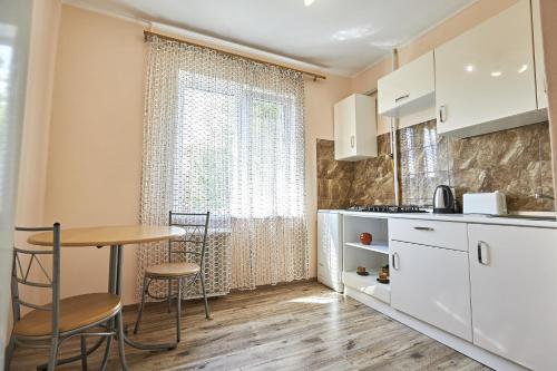 a kitchen with a table and chairs next to a window at Babylon Apartments On Kievskaya Street in Rivne