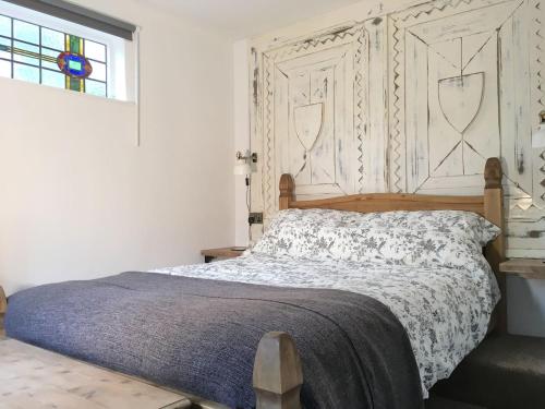 a bedroom with a bed with a wooden headboard and a window at The Hideaway - a charming, unique retreat in Long Ashton, Bristol in Bristol