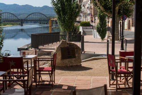 a group of tables and chairs with a view of a river at River Ebro Apartments in Móra d'Ebre