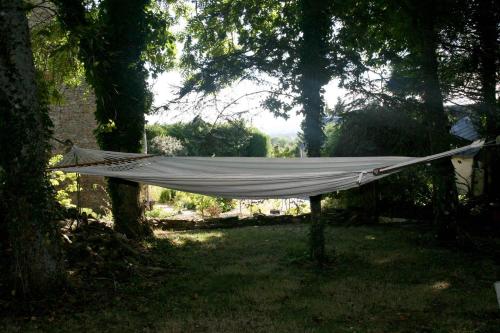 a hammock in the shade of trees in a yard at L'Anctovillière in Anctoville