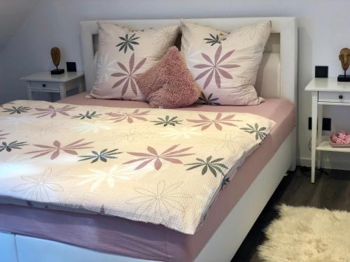 ein Bett mit rosa und lila Blumen drauf in der Unterkunft Ferienwohnung Hünzingen in Walsrode
