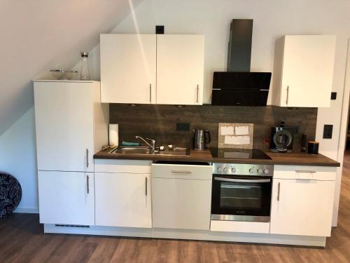 a kitchen with white cabinets and a sink and a stove at Ferienwohnung Hünzingen in Walsrode